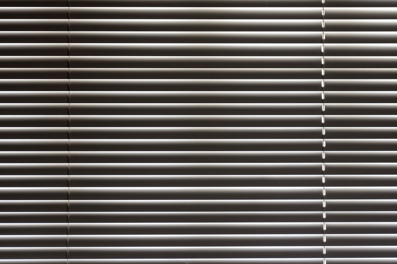 Minimalist close-up of sleek horizontal window blinds with metallic sheen.